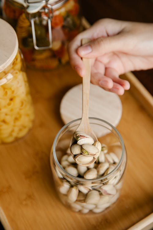 Faceless person showing spoon with pistachios