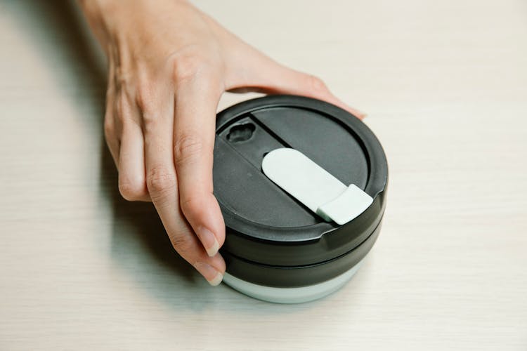 Person Holding Black Round Plastic Lid