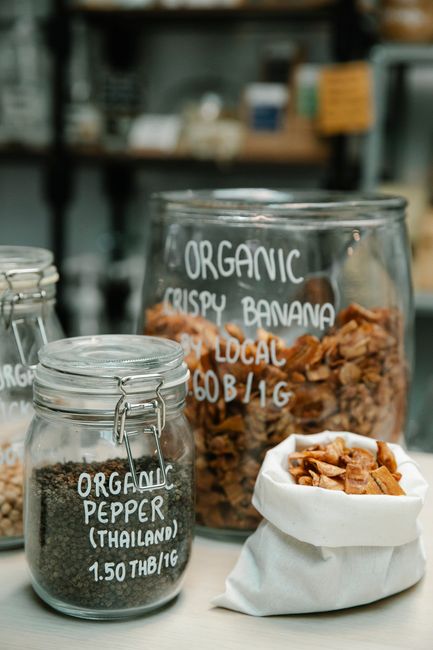 Organic products in glass jars with handwritten labels at a natural food store.