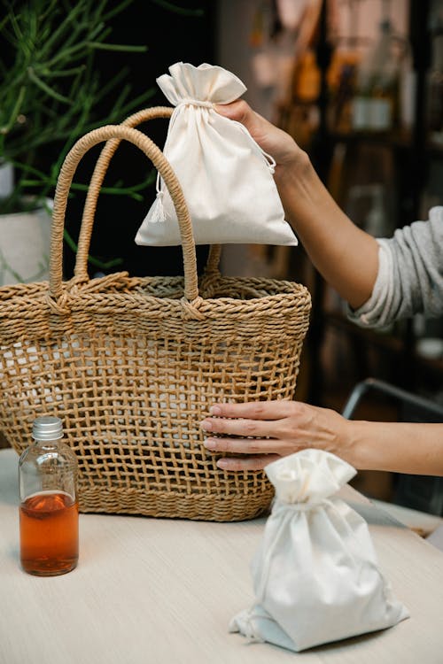 Person Putting Pouch on Woven Basket