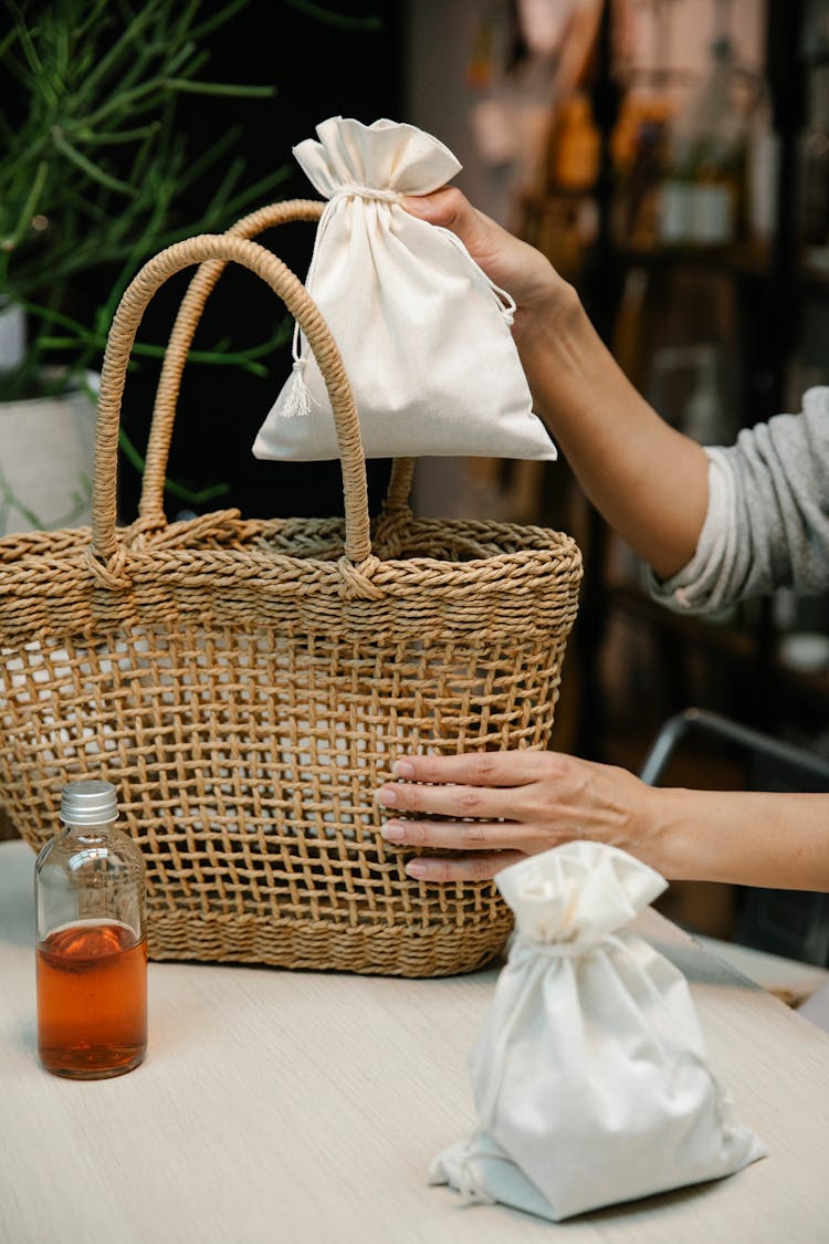 Person Putting Pouch On Woven Basket