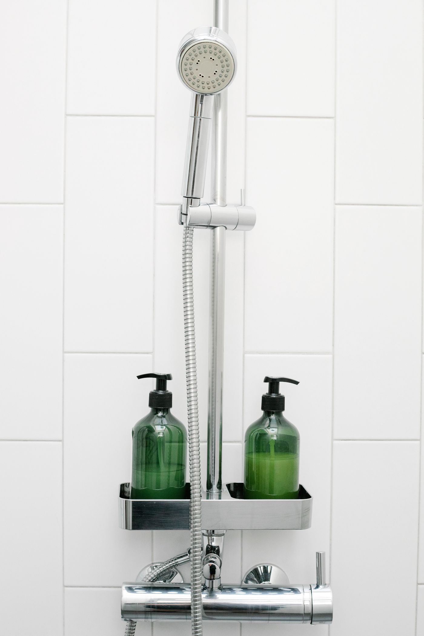 Personal hygiene bottles arranged beside a shower in a bright white daily-care space