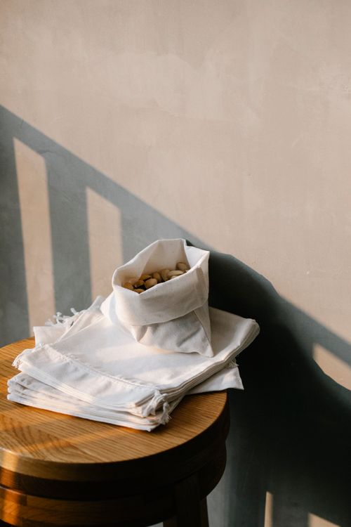 Free ECO friendly sack full of ripe pistachios on white cotton bags placed on wooden table near wall in light room Stock Photo