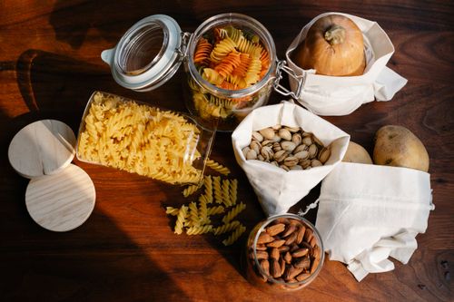 Free Top view jars of raw pasta placed on wooden table near ECO friendly sacks with pistachios and almonds near pumpkin and potatoes Stock Photo