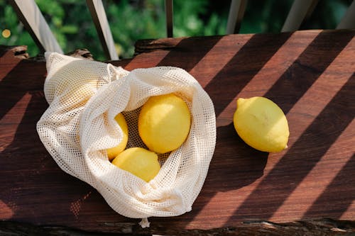 Lemons in bag on wooden surface