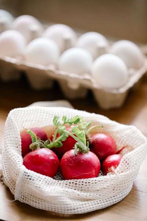 Free Organic fresh radishes in reusable bag placed on kitchen table near eggs box Stock Photo