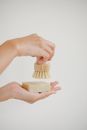 Crop anonymous person demonstrating eco friendly soap and shaving swab against white background