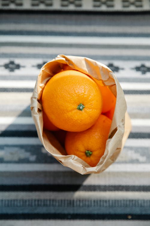 Fresh oranges in parchment bag on table