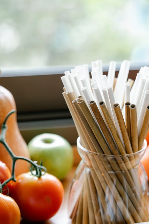 Free Composition of reusable bamboo straws in glass jar placed on table near organic tomatoes and apple Stock Photo
