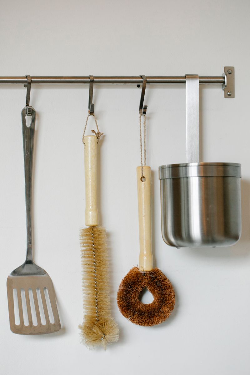 Steel kitchen utensils hanging on a wall rail