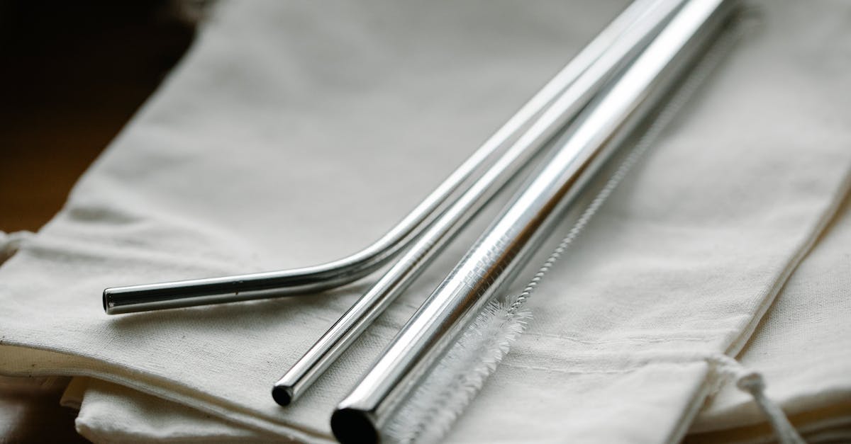 Collection of stainless steel straight and bent straws placed on reusable bags on table