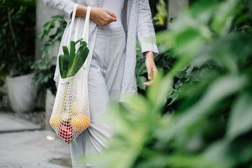 Free Crop unrecognizable woman carrying bag with organic vegetables in garden Stock Photo