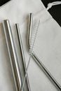 Top view composition of stainless steel straws and brush arranged on white bag on table