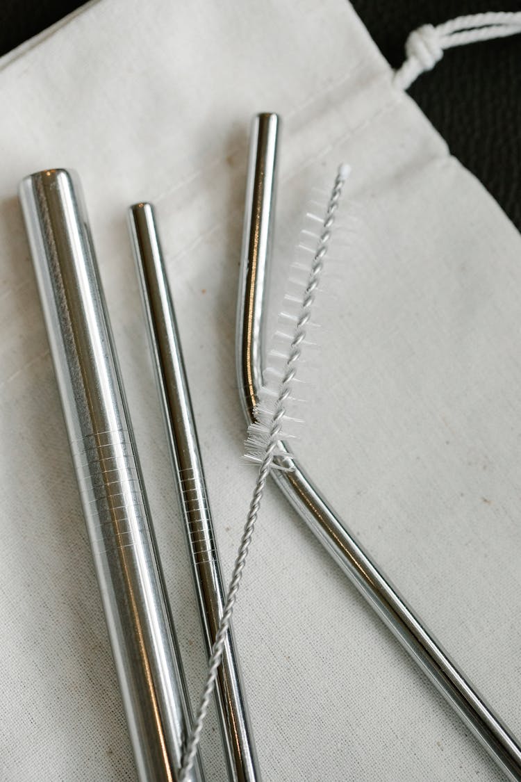 Set Of Steel Straws And Brush On White Bag