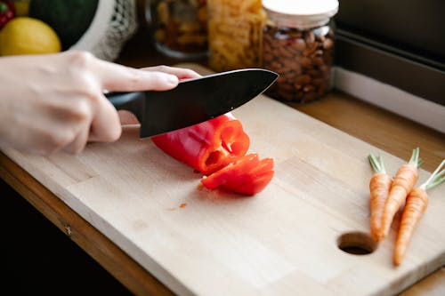 Crop unrecognizable chef cutting bell pepper in kitchen