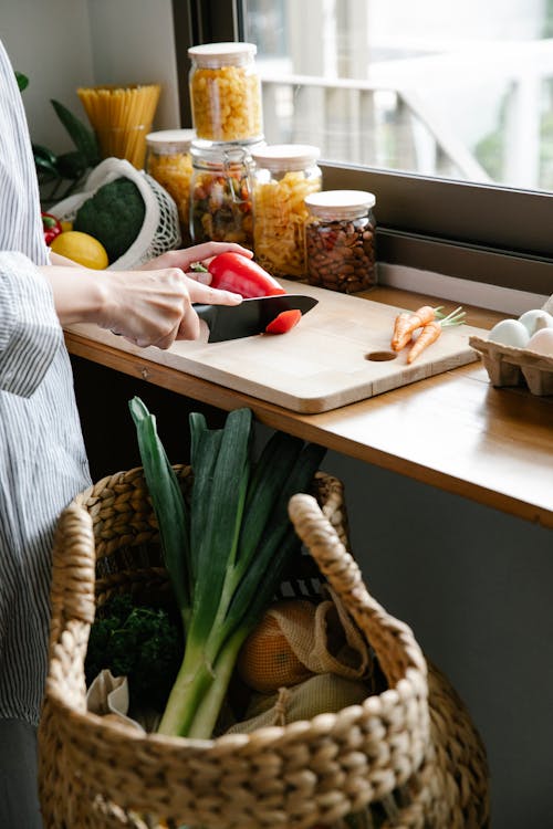Free Crop unrecognizable woman cutting vegetables in kitchen Stock Photo