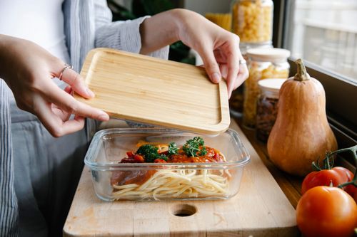 Free From above of crop faceless female covering glass bowl with freshly prepared pasta with tomato sauce while preparing delicious dinner in kitchen Stock Photo