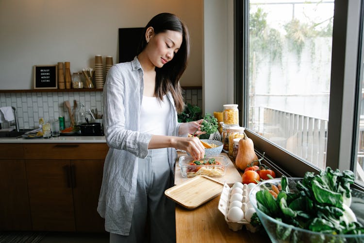 Asian Woman With Pasta On Kitchen Counter