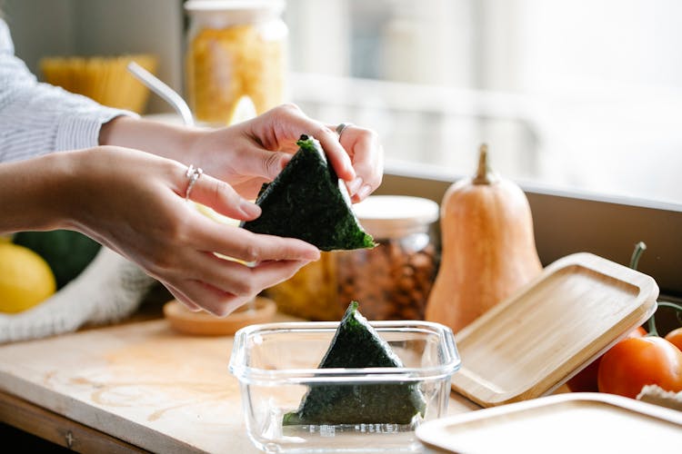 Unrecognizable Woman With Onigiri At Kitchen Counter