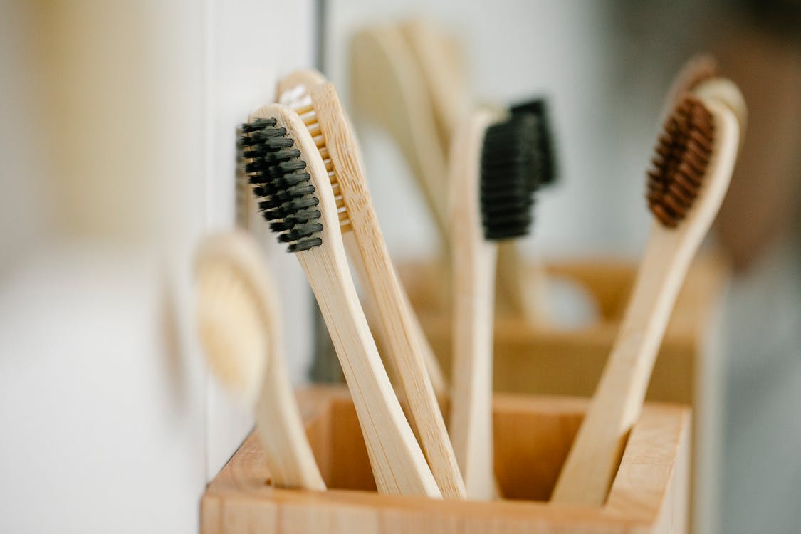 Wooden natural toothbrushes placed in timber container on blurred background at home in daytime
