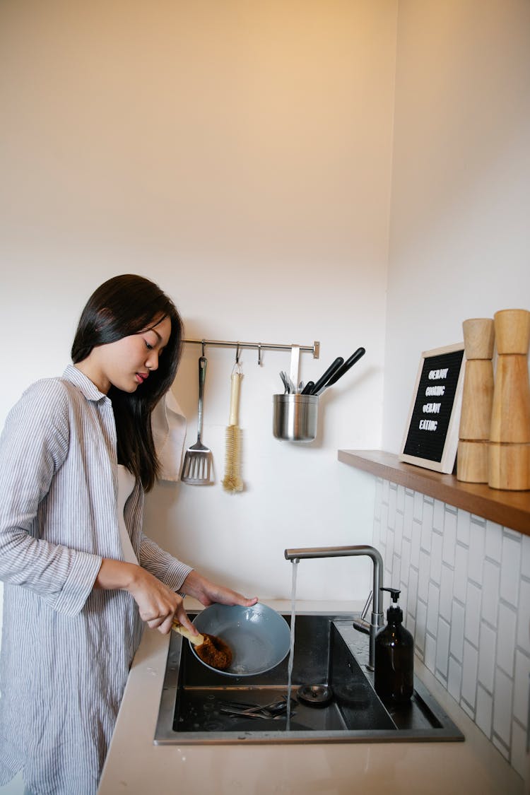 Asian Woman Washing Plate In Modern Kitchen