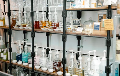 Collection of different plastic bottles with multicolored soap placed on shelves in zero waste shop