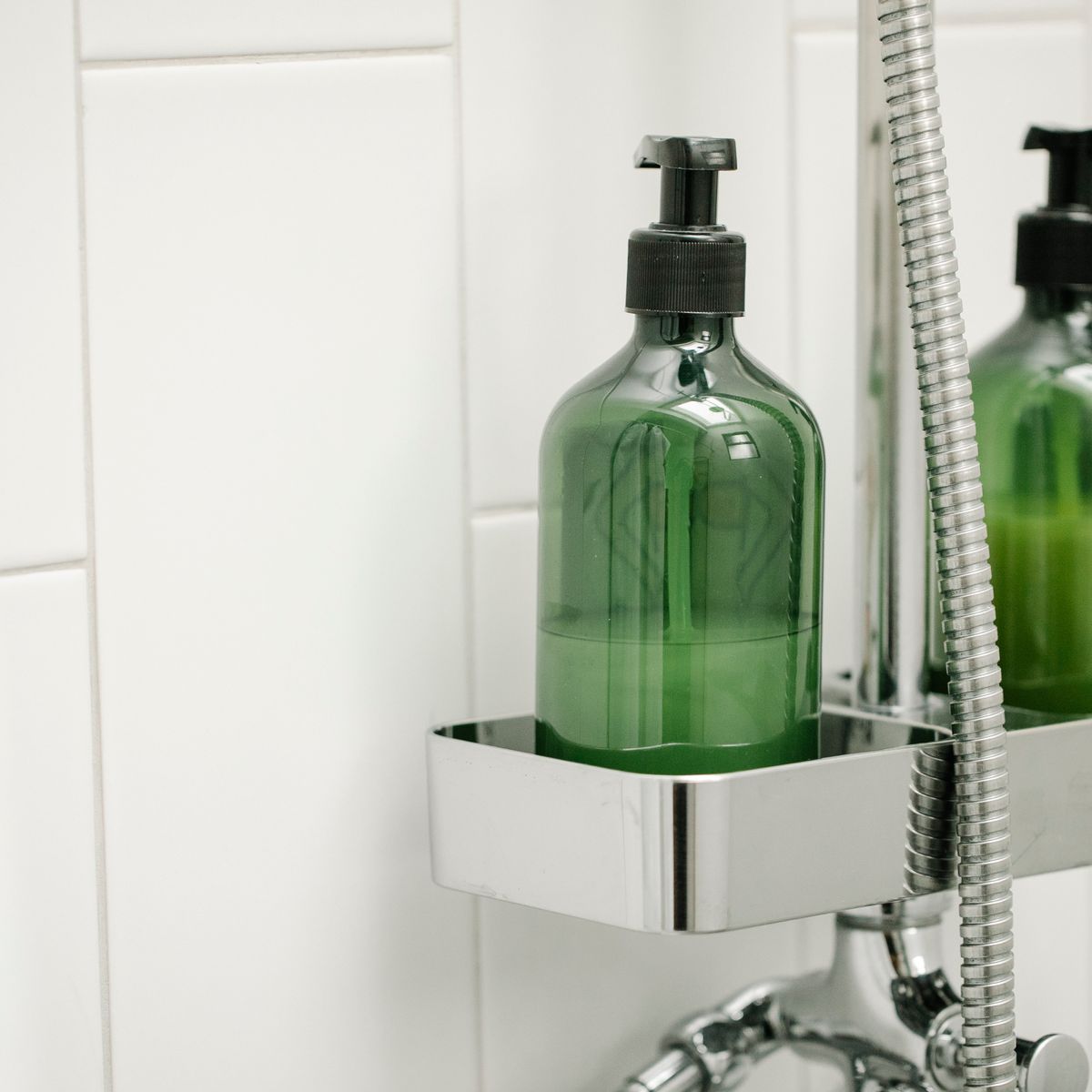 Frascos verdes de banho organizados em suporte dentro do box