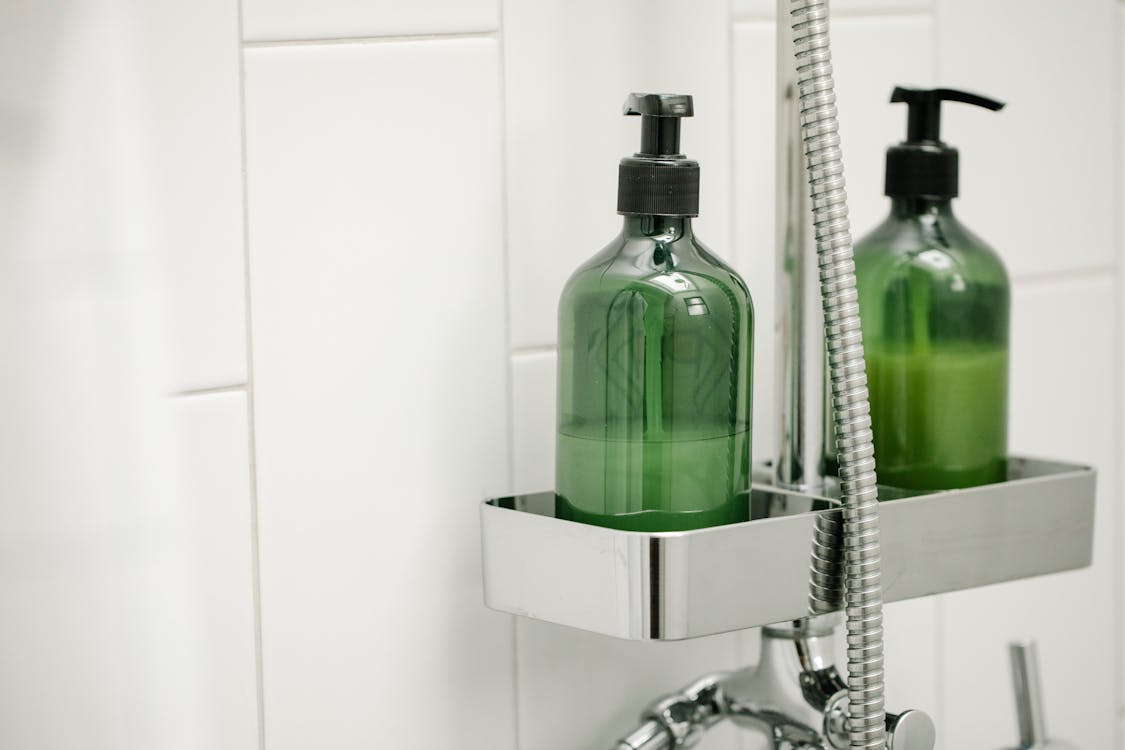 Green dispensers on shelf on shower system
