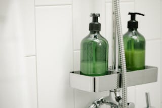 Green dispensers on shelf on shower system