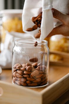 Almonds being poured from a cloth bag into a glass jar, promoting sustainable storage.
