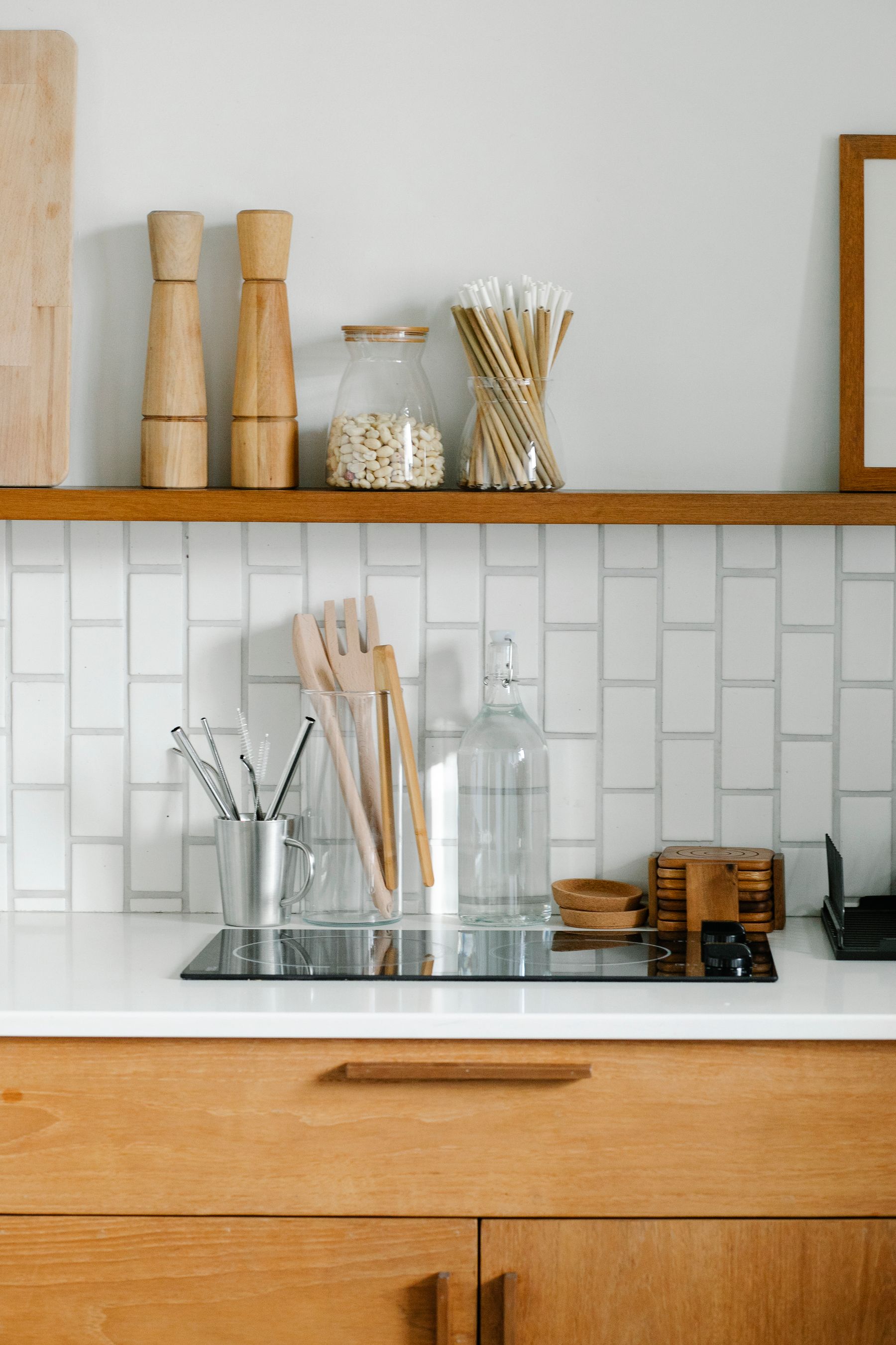 Wood cabinet fronts and a shelf holding jars above a tiled cooking area
