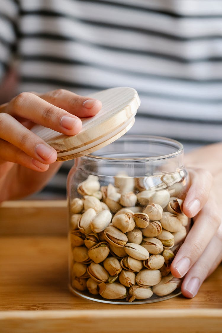 Woman Closing Glass Jar With Pistachios