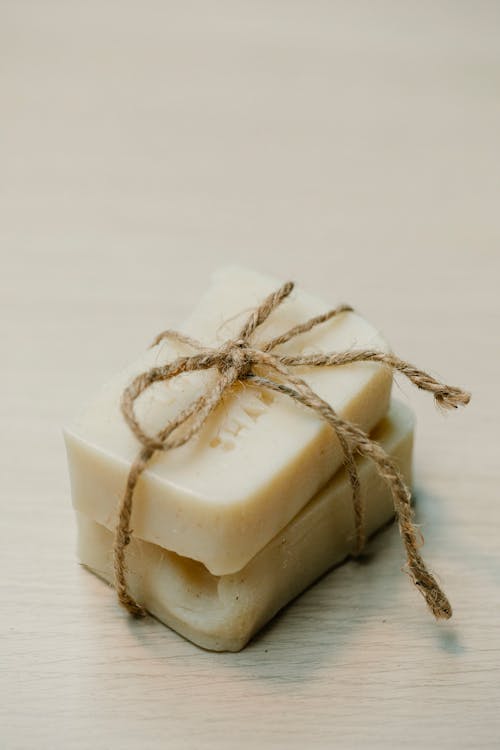 Handmade soap tied with twine on a wooden surface, conveying a rustic and natural aesthetic.