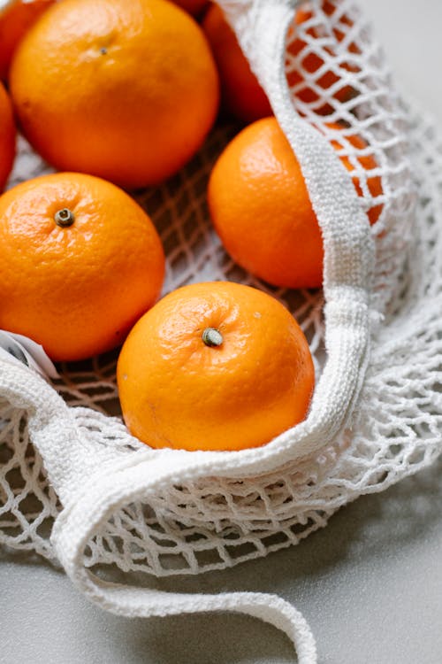 Fresh mandarins placed in string bag · Free Stock Photo