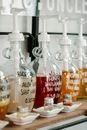 Transparent bottles with pumps and colorful liquid soap placed on wooden shelf in zero waste shop