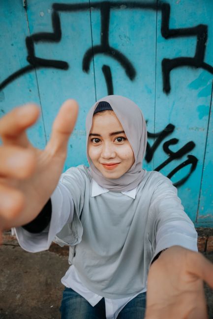 From above of young happy ethnic female smiling and looking at camera near wall with graffiti