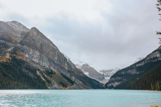 Breathtaking view of Lake Louise surrounded by snow-capped mountains under a cloudy sky.