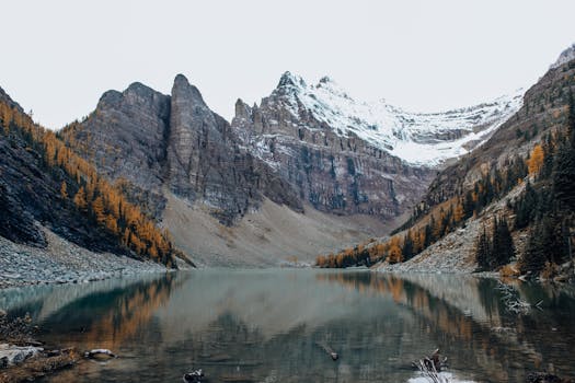 Scenic view of a serene lake mirroring snow-capped peaks during fall.