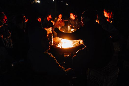 A warm group enjoying a nighttime bonfire outdoors with friends. - Fotografer Sidoarjo