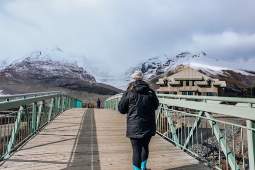 Woman Walking on the Bridge Near Mountains