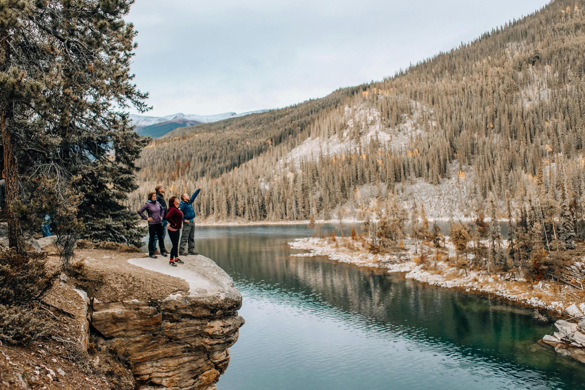 Friends exploring a scenic mountain landscape with a river view on a hiking adventure.