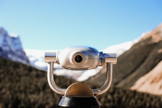 Close-up of modern binoculars with a scenic mountain landscape in the background.