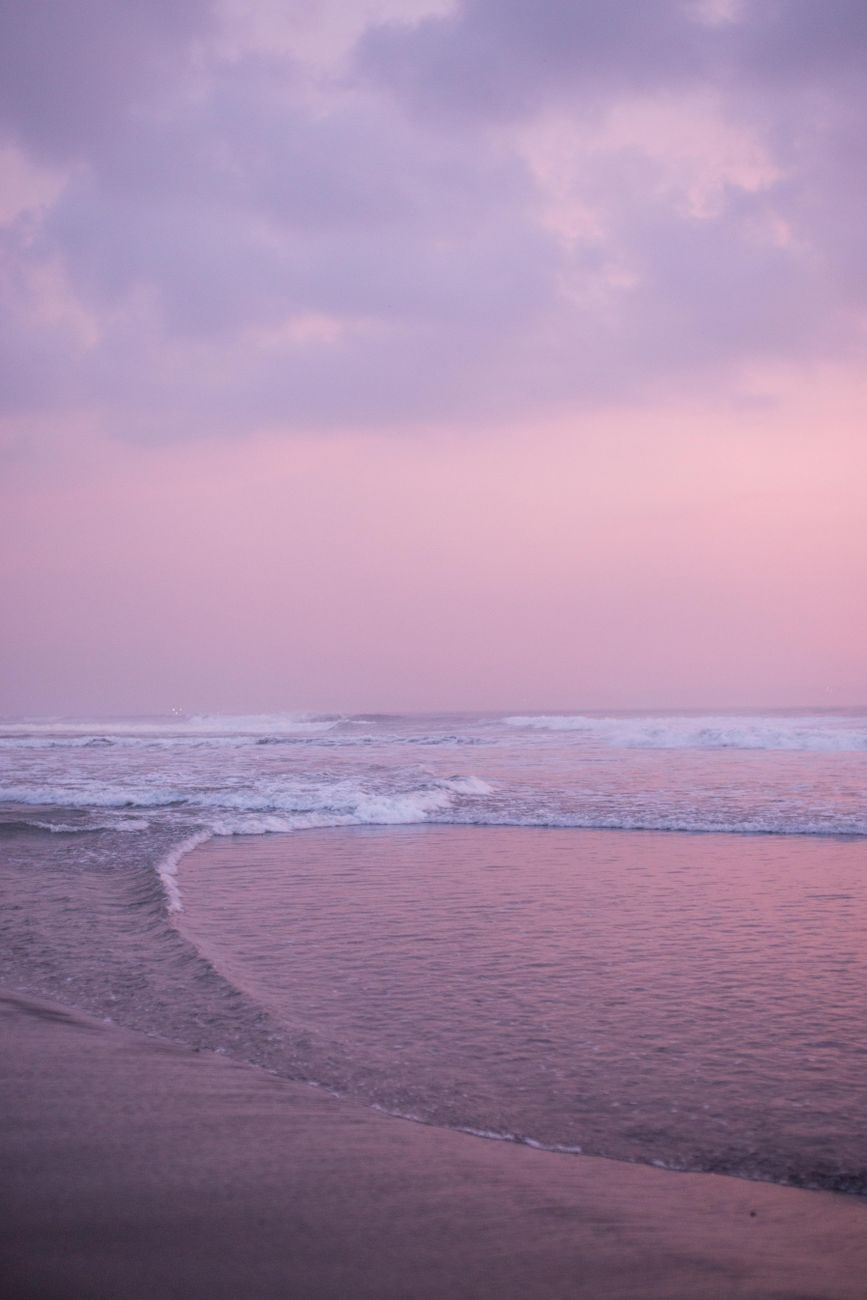 Tranquil beach scene at twilight with soft waves and a pastel sky, creating a peaceful ambiance.