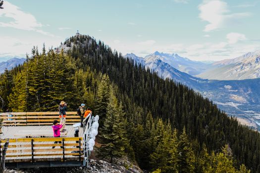Tourists enjoying the stunning view from a mountain observation deck in Canada.