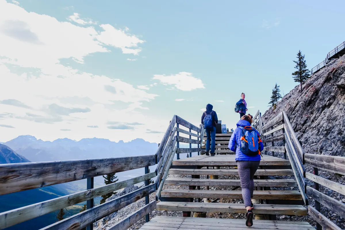 Hikers climbing wooden steps on a ridge with a sweeping mountain view
