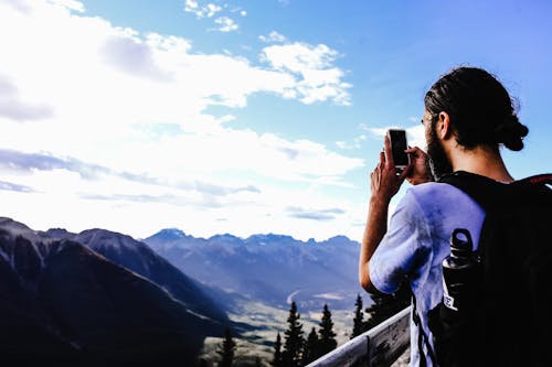 A Backpacker Taking Pictures of Scenic Mountain View using a Smartphone