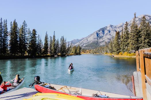 Scenic view of a canoeist on a tranquil mountain lake surrounded by forests.