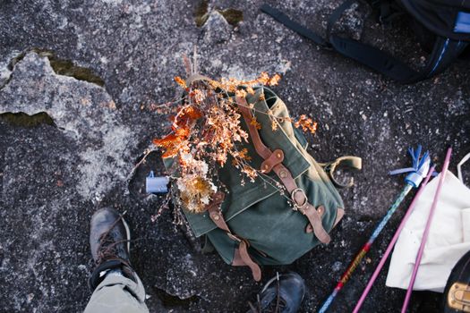 A green backpack with autumn leaves on rocky surface, captured in a high angle view.