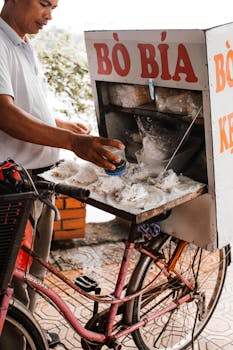 Man making Vietnamese street snack from bicycle cart on a sunny day.