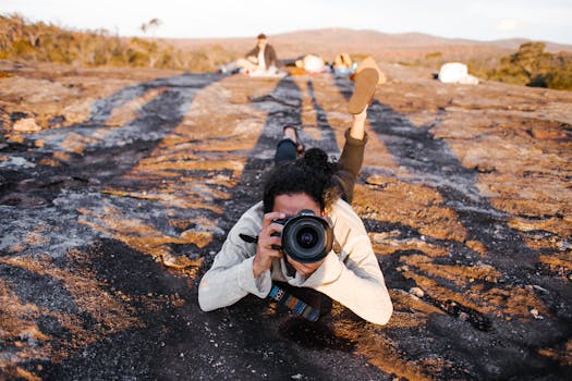 A photographer takes a picture while lying on rugged landscape during a sunny day, embracing the outdoors.